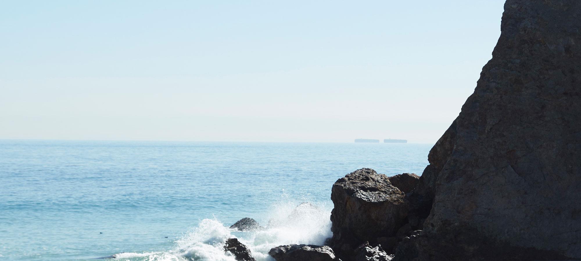 Tinnitus Strand winkender Mensch auf Felsen